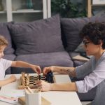 a boy and a boy playing chess on a coffee table