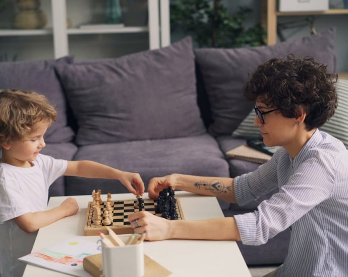 a boy and a boy playing chess on a coffee table