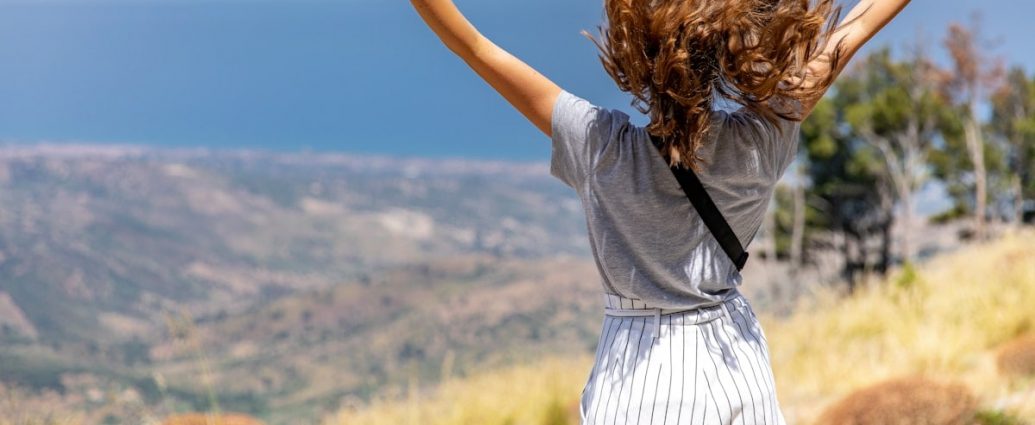 a woman with her hair in the air on top of a hill