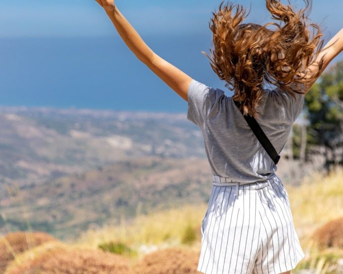 a woman with her hair in the air on top of a hill